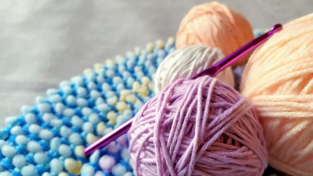 close up photo of a crochet hook and colorful yarns